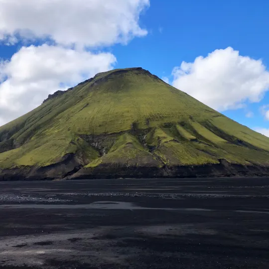 Mountains in Iceland covered in green moss and surrounded by black sand